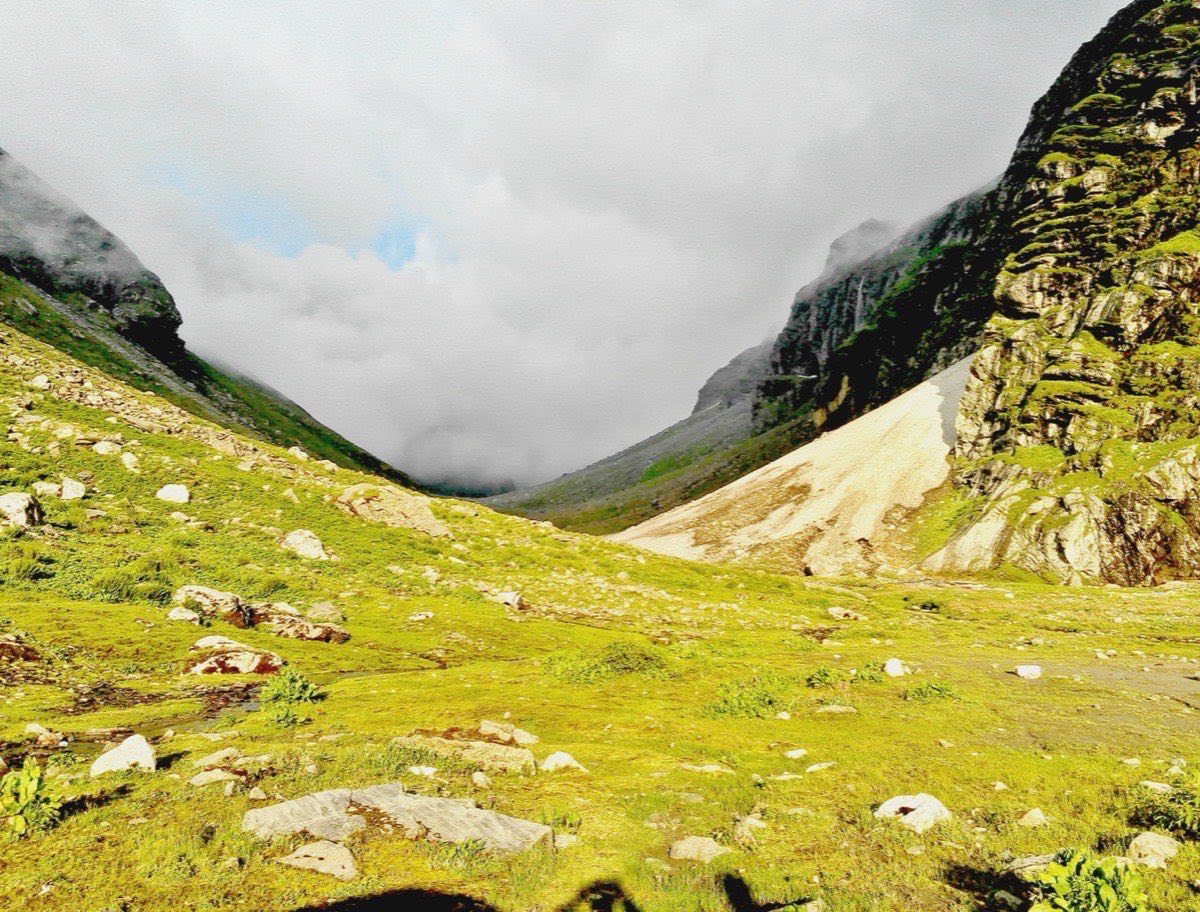 A guide helping trekkers cross a glacial stream